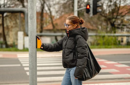 Girl Pressing Traffic Light Button At Pedestrian Crossing In Spring