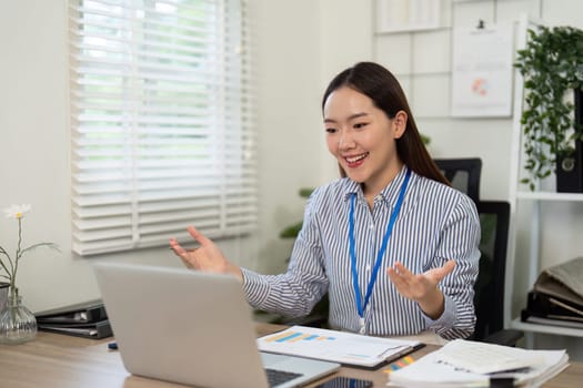 A smiling businesswoman engages actively in a video call, showcasing effective communication and enthusiasm in a modern office setting.