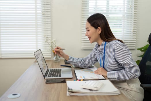 A cheerful businesswoman engaging with her laptop to analyze data, showcasing a positive remote work environment.