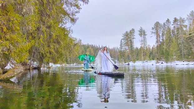 Two girls in white and green costumes act out a creative role-play by a calm lake, symbolizing the shift from winter to spring.