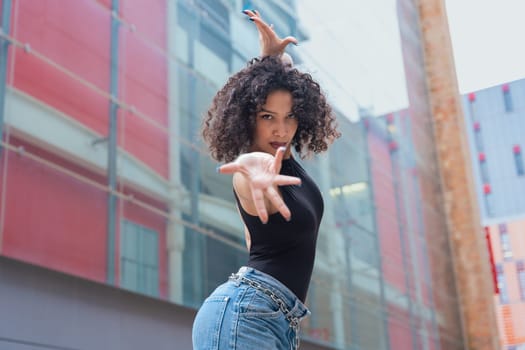 African American woman dancing in a creative pose between benches in an urban setting. She wears casual clothes and shows balance, strength, and expression. Concept of movement, art, and freedom.