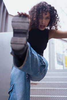 African American woman dancing in a creative pose between benches in an urban setting. he wears casual clothes and shows balance,strength, and expression. Concept of movement, art,and freedom.Vertical