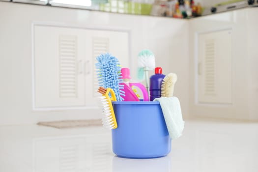 House cleaning essentials. A plastic bucket with detergent, brushes, and supplies sits on the kitchen floor, making routine cleaning tasks easier and more efficient.