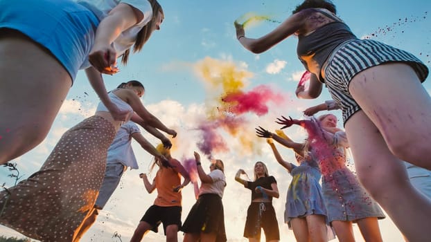 Group of cheerful school friends throwing colorful powder in the air while enjoying a vibrant holi festival celebration at sunset