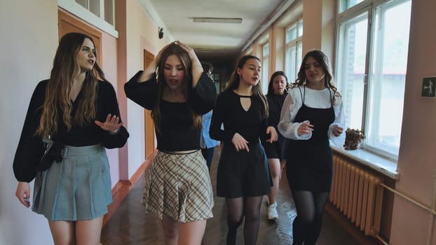 Group of teenage girls walking through a school hallway, chatting animatedly and gesturing, enjoying their time together after class