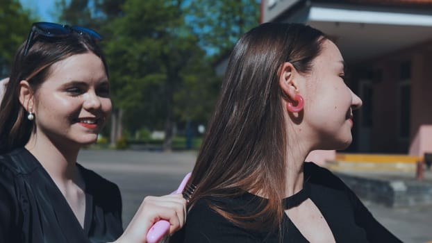 Two teenage friends bonding after school, one gently brushing the other's hair with a pink brush on a sunny afternoon