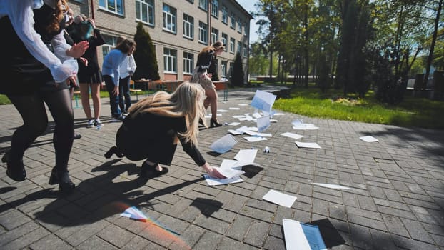 Happy students celebrating their exam completion by joyfully throwing papers in the air, enjoying freedom in the schoolyard