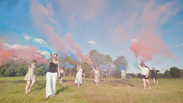 Group of teenagers walking in a field, holding colored smoke bombs, celebrating summer and freedom
