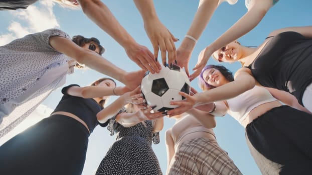 Group of high school girls forming a circle, holding a soccer ball together, enjoying their summer break