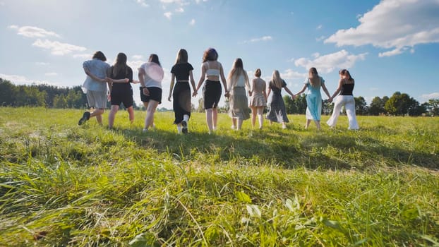 Group of high school students walking together in a field holding hands, enjoying their summer break