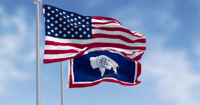 Wyoming state flag and the american flag waving together on a clear day. Silhouette of an American bison with the state seal on its trunk. 3d illustration render. Selective focus. Rippling fabric