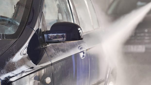 High pressure water jet cleaning a car at car wash