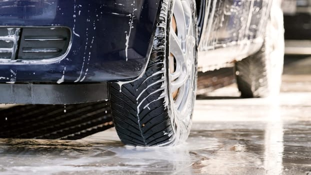 Droplets of detergent drip off the body of a passenger car