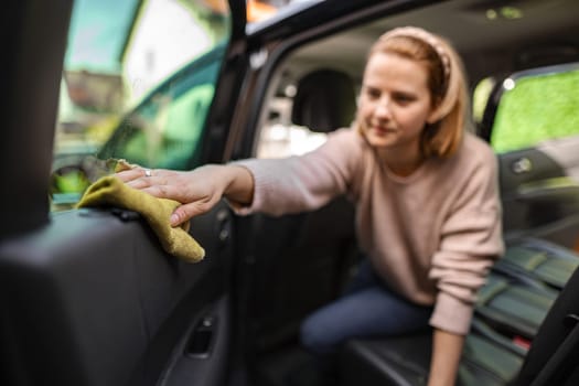 A woman meticulously wipes down her car's interior.