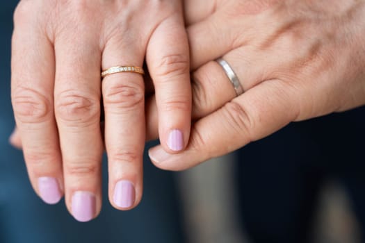 Married elderly couple holding hands with rings wedding day
