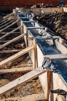 Building strip foundation for new house, using wooden formwork, concrete, reinforcement and waterproofing