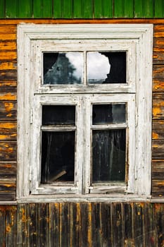 Old broken window in weathered wooden wall reflecting cloudy sky, representing decay, neglect, and the passage of time