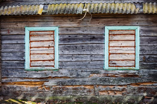 Boarded windows of an old abandoned wooden house with decaying and neglected facade