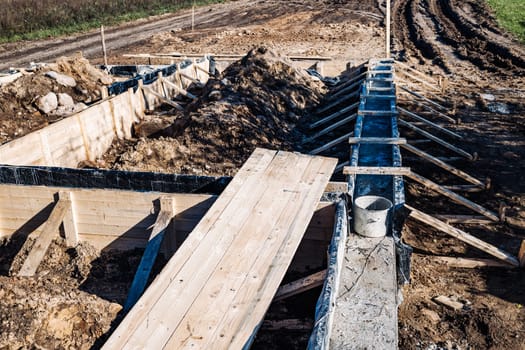 Wooden formwork is being prepared for pouring concrete for the foundation of a building under construction