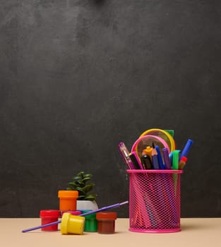 Pink glass with writing utensils, paint cans, brush, creativity or school activities