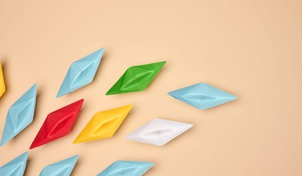 Multicolored origami paper boats are placed on a beige background, symbolizing diversity