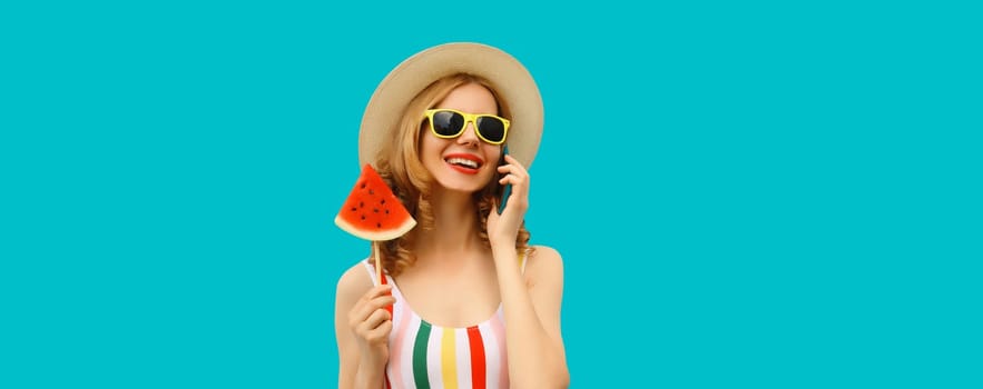 Summer vacation, happy joyful woman calling on phone with fresh fruits, lollipop or ice cream slice of watermelon, wear tourist hat, cheerful girl talking on smartphone on blue studio background