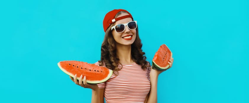 Summer portrait of happy young woman eating fresh slice of watermelon on blue studio background