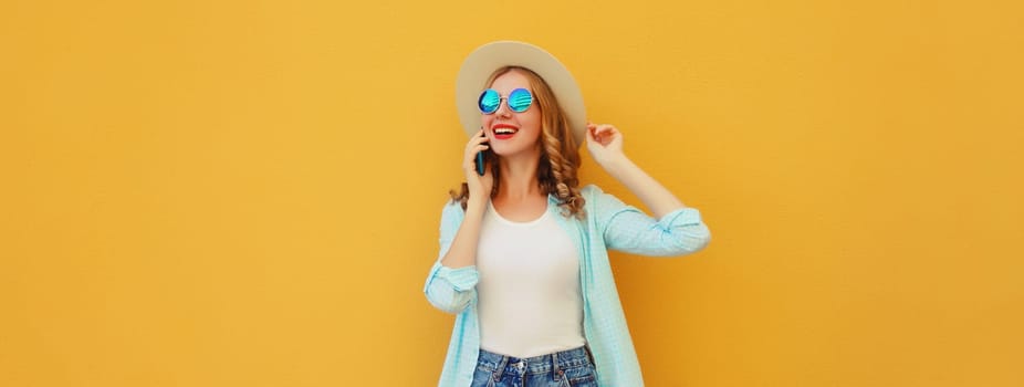 Happy cheerful young woman laughs calling on phone, girl talking on the smartphone in summer tourist straw hat looks away on yellow background