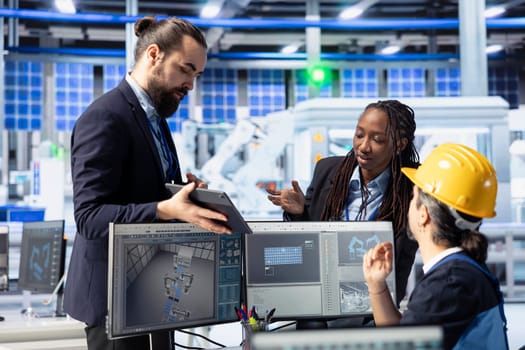 Solar panels plant manager showing employees factory energy consumption on tablet. Photovoltaics facility supervisor using device to present workers use of manufacturing resources