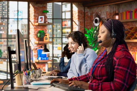 Friendly customer service employee tracking support ticket in dedicated company software on computer. Upbeat call center agent at office desk creating support ticket for customer calling