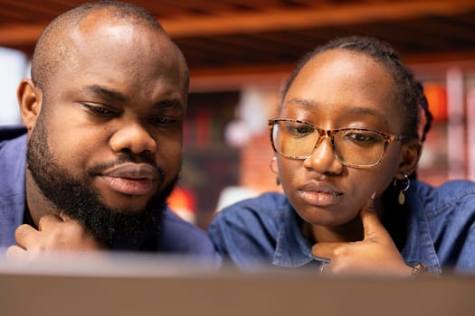 African American man and woman at home office analyzes online business trends, using teamwork and technology to manage their freelance careers and boost tasks efficiency. Networking.