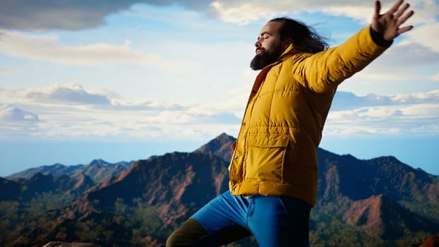 Happy adventurer embraces the thrill of standing at the top of the mountain, feeling the power of accomplishment. Awe inspiring mountain range with peaceful sky and vast wilderness. Camera A.