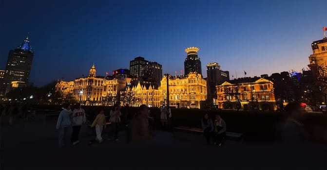 Shanghai, China – April 1, 2025: View of The Bund at night with historic colonial buildings illuminated along the Huangpu River in Huangpu District, full of visitors and city lights.
