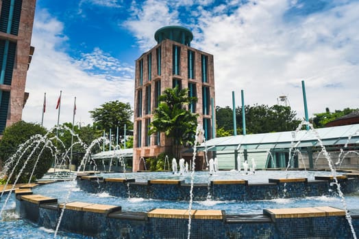 Singapore, Singapore - 4 April 2025: Water fountain splashes in front of tower and palm trees at Resorts World Sentosa on Sentosa Island
