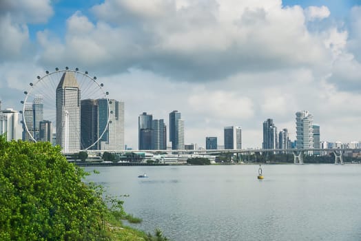 Singapore, Singapore - 4 April 2025: City skyline view with Singapore Flyer and modern buildings near the bay under cloudy sky, seen from Marina Bay area.