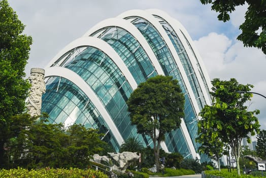 Singapore, Singapore - 4 April 2025: Iconic Cloud Forest dome in Gardens by the Bay framed by trees and modern path on a bright tropical afternoon.