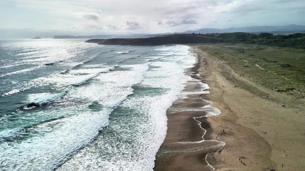 A serene and tranquil beach landscape showcasing waves crashing gently on the sandy shoreline beneath a cloudy sky