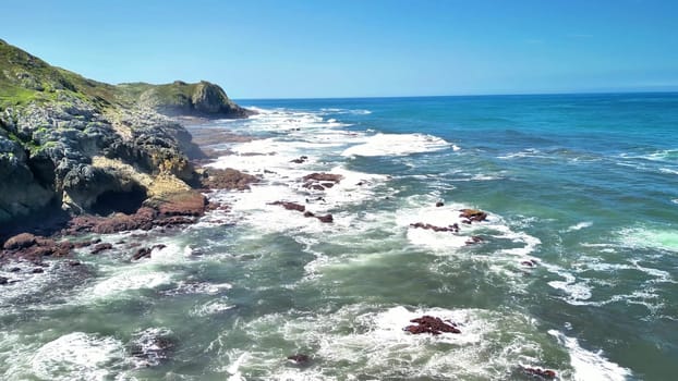 A breathtaking scene depicting the majestic ocean waves crashing against rocky shores under a clear blue sky