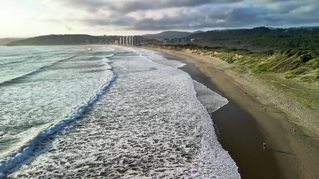 A stunningly beautiful beach scene captures gentle waves rolling onto the sandy shore, close to a vibrant city skyline
