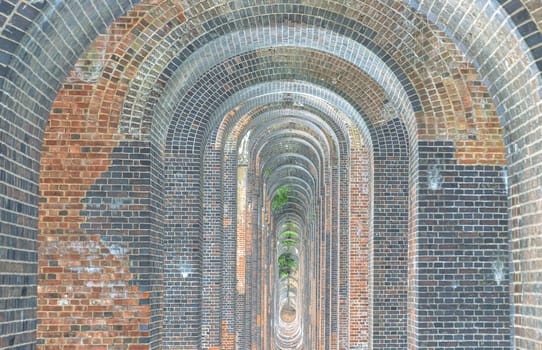 Sussex, UK - May 21, 2025 - The semi-circular arches vaulting supporting brick piers, composed of traditional red bricks topped with smooth limestone and has been described as “the most elegant viaduct in Britain”. Ouse Valley Viaduct or Balcombe Viaduct (Railway viaduct) carries the Brighton Main Line over the River Ouse in Sussex. use it as your Wallpaper, Poster and Space for text, Selective focus.