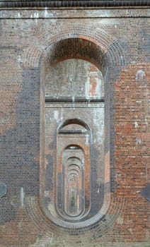 Sussex, UK - May 21, 2025 - The semi-circular arches vaulting supporting traditional red brick piers with smooth limestone of Architectural splendour of Ouse Valley Viaduct or Balcombe Viaduct (Railway viaduct) has been described as “the most elegant viaduct in Britain” carries the Brighton Main Line over the River Ouse in Sussex. use it as your Wallpaper, Poster and Space for text, Selective focus.