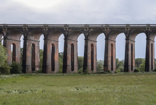 Sussex, UK - May 21, 2025 - Architectural splendour of Ouse Valley Viaduct or Balcombe Viaduct (Railway viaduct) with sky background, carries the Brighton Main Line over the River Ouse in Sussex, has been described as “the most elegant viaduct in Britain”, The semi-circular arches vaulting supporting brick piers, composed of traditional red bricks topped with smooth limestone. use it as your Wallpaper, Poster and Copy space, Selective focus.