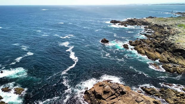 A breathtaking aerial view of the coastline, featuring turquoise waves crashing against rocky formations.
