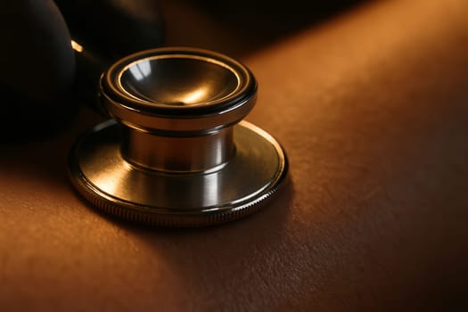 Extreme close-up of a stethoscope diaphragm pressed against patient’s skin under warm tungsten light