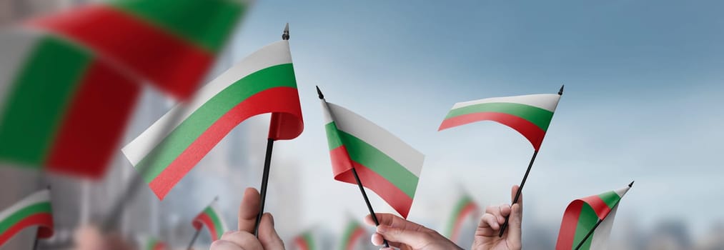 Bulgaria flags in their hands on a blurred urban background. The photo illustration was created without the use of artificial intelligence, only using Photoshop.