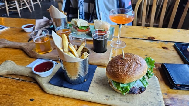 Enjoy a tasty burger with crispy fries and a selection of craft beers on a rustic wooden table. Ideal for sharing with friends or savoring solo, this meal is both delicious and satisfying.