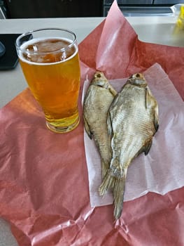 A classic pairing of dried fish and beer, ideal for a casual snack or meal. This still life captures traditional flavors and simple pleasures, perfect for food publications.