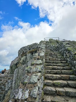 A stone stairway leads up a mountain, inviting exploration of nature s beauty. The blue sky and clouds create an atmospheric backdrop, making it an ideal stock scene for adventure.