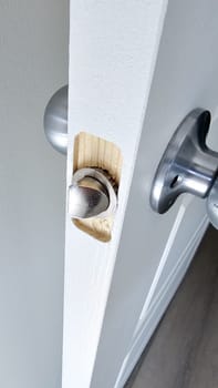 Close-up of a damaged door latch revealing the exposed wood frame, highlighting a home repair project. This image illustrates the interior fix needed for a malfunctioning door latch.