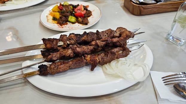 A visually appealing dish featuring grilled meat skewers alongside a fresh salad and crispy onion rings. This meal is elegantly presented on a white plate, ideal for menus or food blogs.